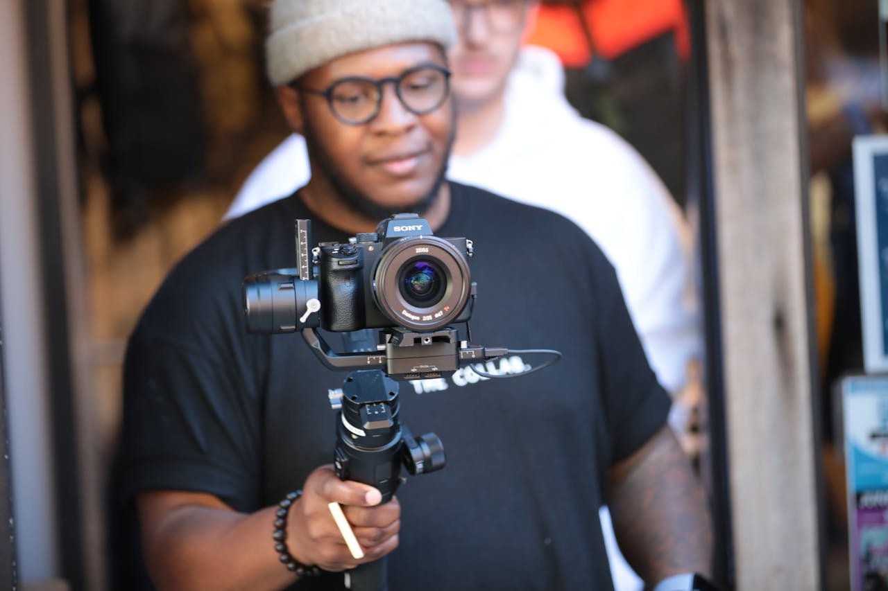 why-choose-us Black male videographer with a modern camera filming indoors, capturing a laid-back scene.